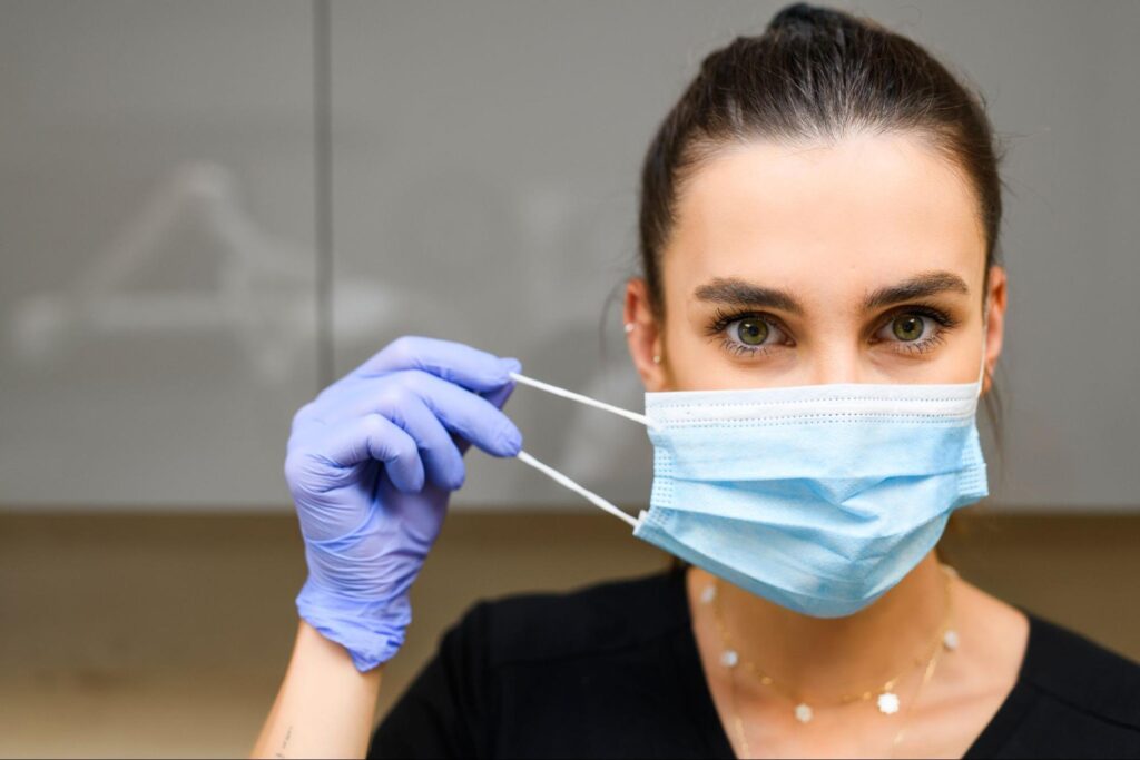 Dentysta w rękawiczkach zdejmujący maseczkę ochronną