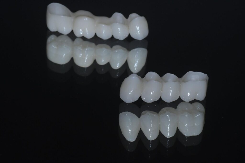 Korony cyrkonowe do zębów prezentowane na ciemnym tle