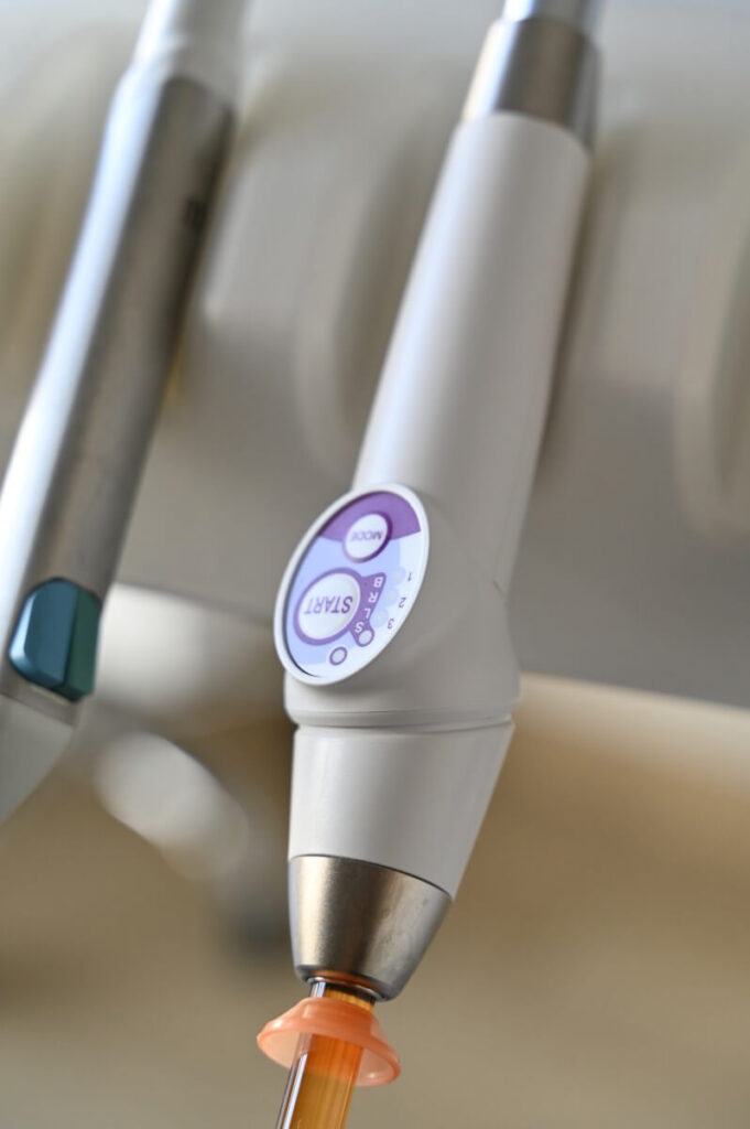 Nowoczesna bezprzewodowa lampa polimeryzacyjna z panelem sterowania, umieszczona w unicie stomatologicznym.